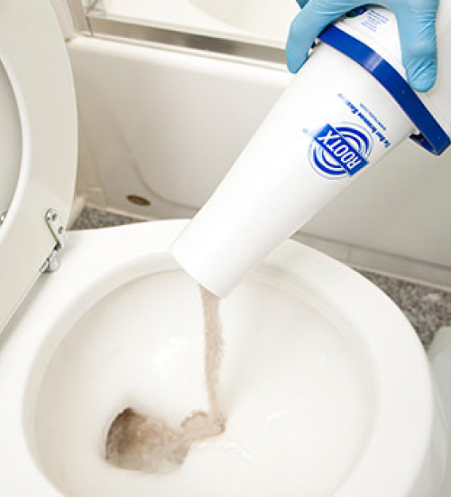 Plumber pours RootX into a toilet seat